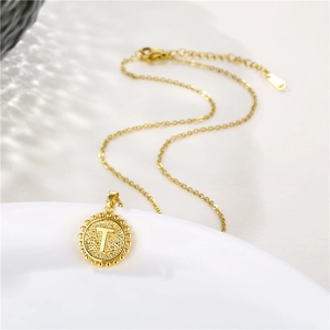 Macro shot of gold stainless steel necklace with round letter T pendant and beaded edge