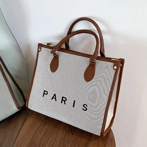 Große beige Canvas-Tragetasche mit braunem Lederbesatz und PARIS-Schriftzug auf Holz