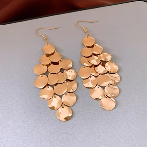 Detail of layered gold round sequin earrings with a metallic shimmering tiered design