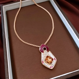 Detail view of vintage gold necklace with amber and magenta stones in a brown box
