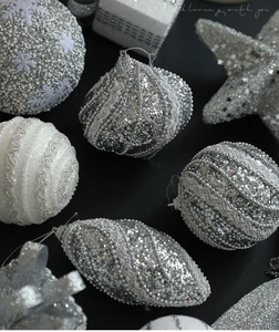 Macro shot of silver Christmas ornaments with glitter patterns and bead textures