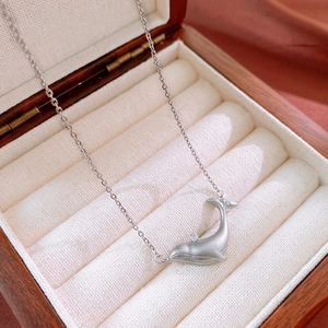 Macro shot of a minimalist whale tail pendant with zircon stones in a wooden jewelry box