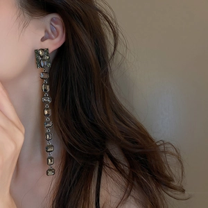 Close-up of model wearing long dark square crystal tassel earrings with a vintage finish