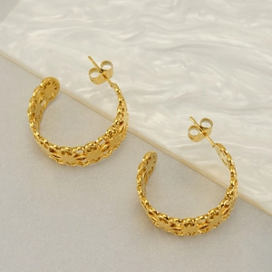 Golden hollow floral geometric stainless steel C-shaped hoop earrings on textured board