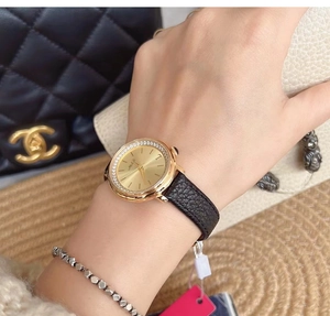 Close-up of luxury gold watch with diamond bezel and black leather strap on wrist