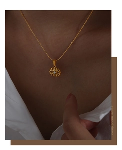 Close-up of golden evil eye pendant necklace with white stone inlay worn on neckline