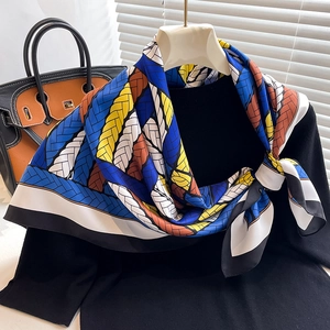 Detailed close-up of patterned silk scarf with braided textures and color block design