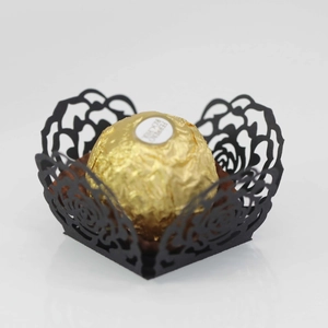 Detail of laser-cut black paper chocolate wrapper with rose pattern and gold foil candy