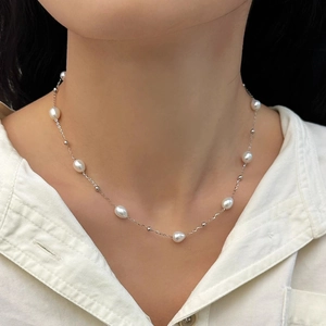 Close-up of minimalist freshwater pearl necklace on model neck with silver chain