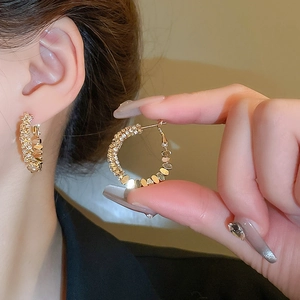 Gros plan de boucles d'oreilles créoles dorées en C avec zircons scintillants