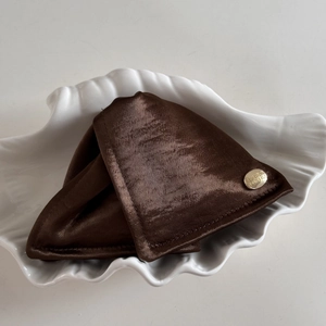 Vue détaillée de la pince à cheveux en satin marron avec étiquette dorée en métal