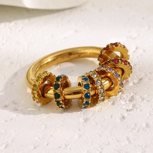 Détail macro d'une bague plaquée or 18 carats avec engrenages sertis de zircons colorés
