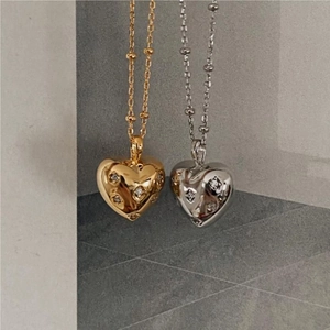 Close-up of gold and silver puffed heart pendants with zircon stones on bead chains