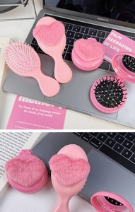 Pink heart-shaped plush hairbrush and mirror vanity set placed on a laptop