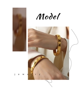 Detail view of a 18k gold plated stainless steel cuff bracelet with clover flower relief