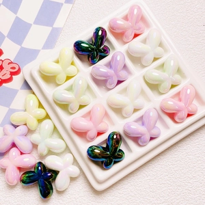 Macro detail of aurora gradient resin butterfly beads in a white organizer tray