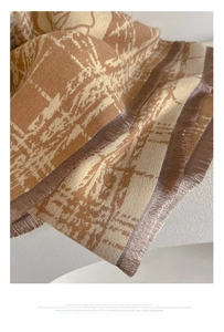 Close-up of beige jacquard cashmere-feel scarf showing delicate snowflakes and fringe