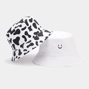 Detail of reversible bucket hats featuring cow print and minimalist smile icon design