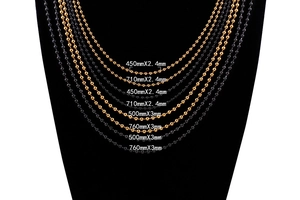Detailed view of stainless steel bead chains in gold and black on a black mannequin