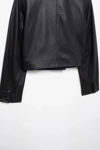 Detail view of the black leather jacket's hem and cuffs featuring three matching buttons