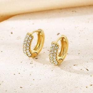 Détail de petites créoles dorées avec sertissage pavé de cristaux brillants sur pierre