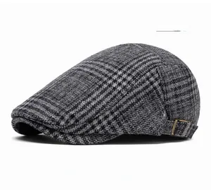 Detail of gray houndstooth flat cap featuring side metal buckle and wool texture