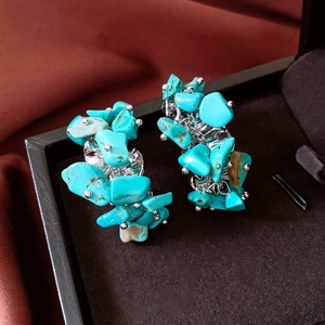 Vintage silver C-shaped hoop earrings with irregular turquoise stones on a velvet display