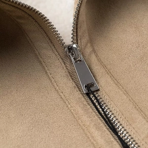 Détail d'une fermeture éclair en métal sur une veste beige en daim pour femme
