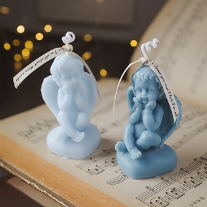 Handmade blue angel-shaped soy wax candles placed on vintage sheet music with warm lights