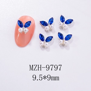 Detail view of 9.5x9mm butterfly nail charm with blue crystals and white pearls