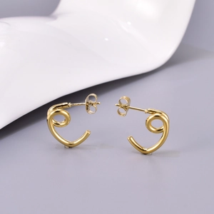 Détail macro de boucles d'oreilles créoles spirales en acier inoxydable doré poli