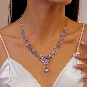 Detail of silver necklace featuring purple marquise crystals and flower vine design on model
