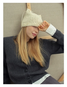 Close-up of cream knit cat ear hat with ribbon bows and handmade crochet texture