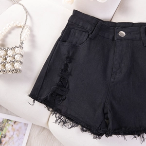 Dettaglio della trama strappata e dell'orlo a taglio vivo sugli shorts in denim nero