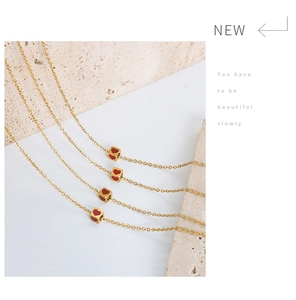 Detail of gold square pendant necklaces with red heart motif on stone display