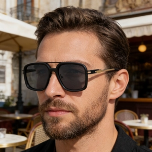 Male model wearing black square frame sunglasses with golden arrow hinge detail