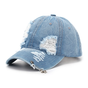 Close-up of light blue distressed denim baseball cap with cross pendant pin detail