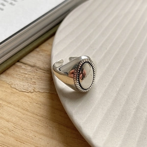 Detail of oval vintage silver ring with textured edges on a white ceramic tray