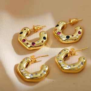 Polished C-shape gold earrings set with colorful crystals and pearls on silk
