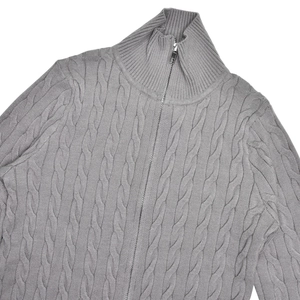 Détail d'un pull gris en maille torsadée avec col montant et fermeture éclair métallique