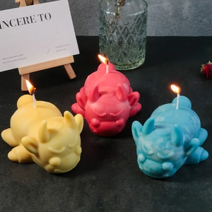 Three colorful cute monster scented candles lit on a stone surface in a cozy home setting