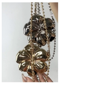 Detail of flower-shaped metallic evening bags with bead chains in gold and silver