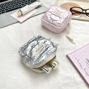Close-up of quilted heart-patterned pouch and silver star-textured makeup bag with zipper