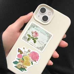 Detail of vintage pink floral stickers on a cream phone case with French postcard motifs