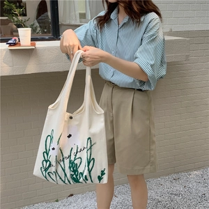 Close-up of white canvas tote bag with chamomile print and Don't ever change quote