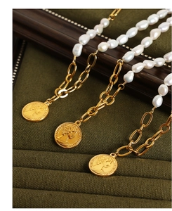 Close-up of vintage freshwater pearl necklaces with Elizabeth II coin pendants in a green box