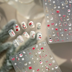 Macro detail of 3D gold embossed Christmas nail art stickers with snowman and tree