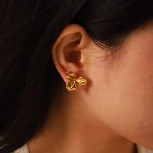 Gros plan d'une boucle d'oreille fleur en or 18 carats avec texture sur le modèle
