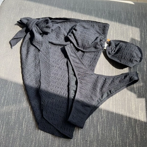 Detail of black three-piece bikini set featuring textured seersucker fabric and sarong