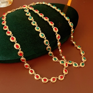 Détail du collier vintage doré avec des pierres précieuses ovales rouges et vertes